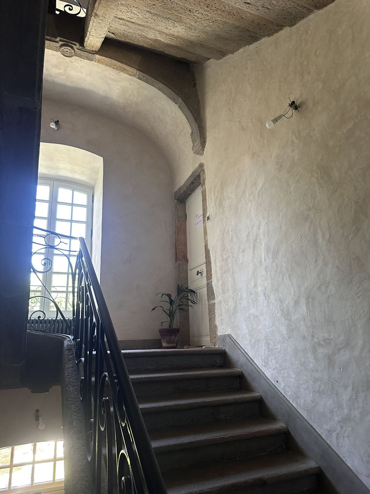 La même cage d'escalier avant travaux, murs gris et irréguliers