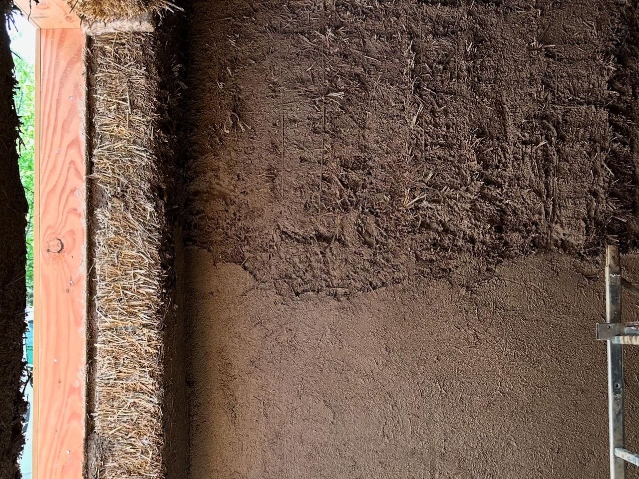 Botte de paille apparente à gauche et corps d'enduit terre en cours d'application à droite
