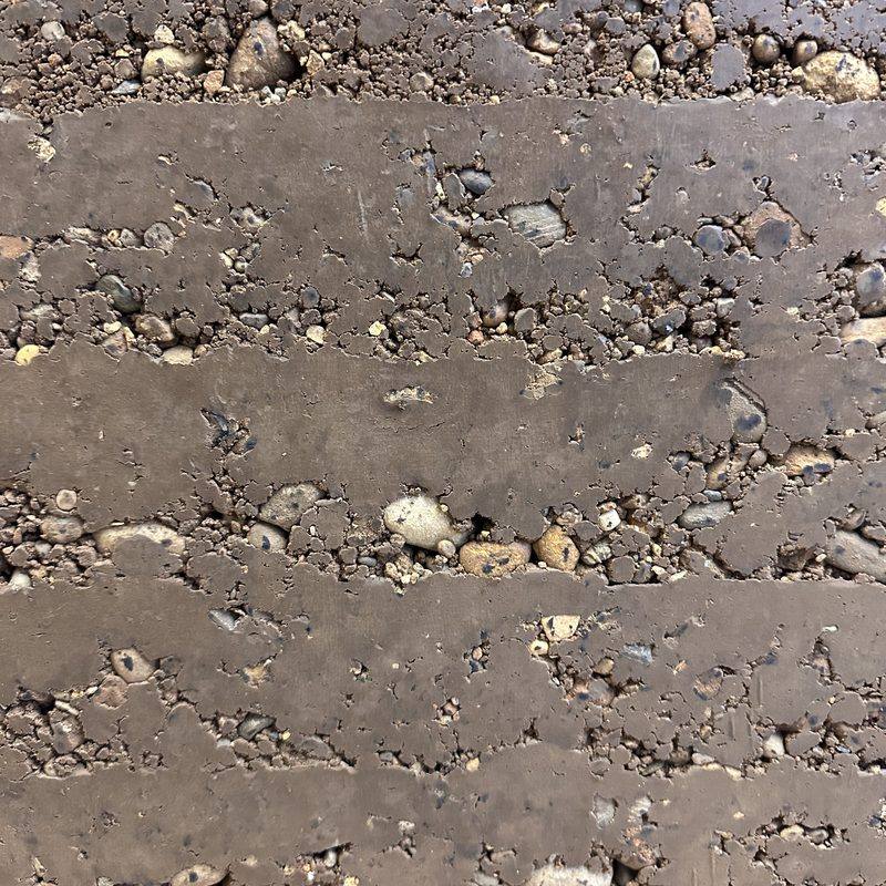 Macro d'un bloc de pisé, granulats et strates de compactage visibles