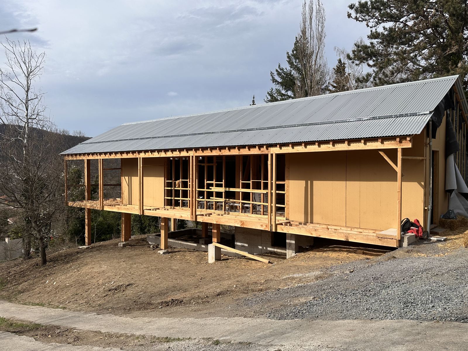 Façade de la maison en cours de chantier, ossature bois sur pilotis et panneaux de fibre de bois