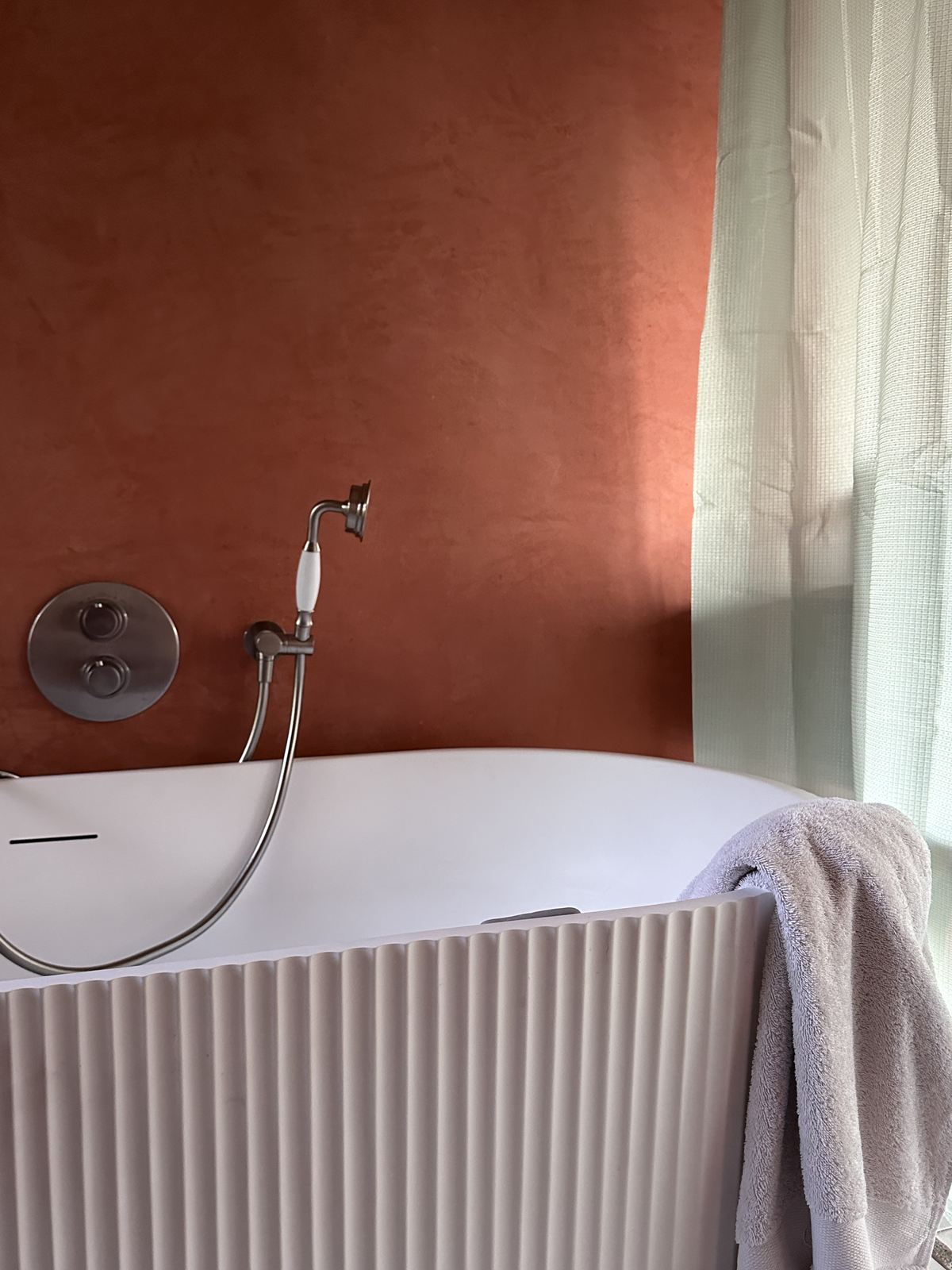 Baignoire devant un mur en tadelakt rouge orangé