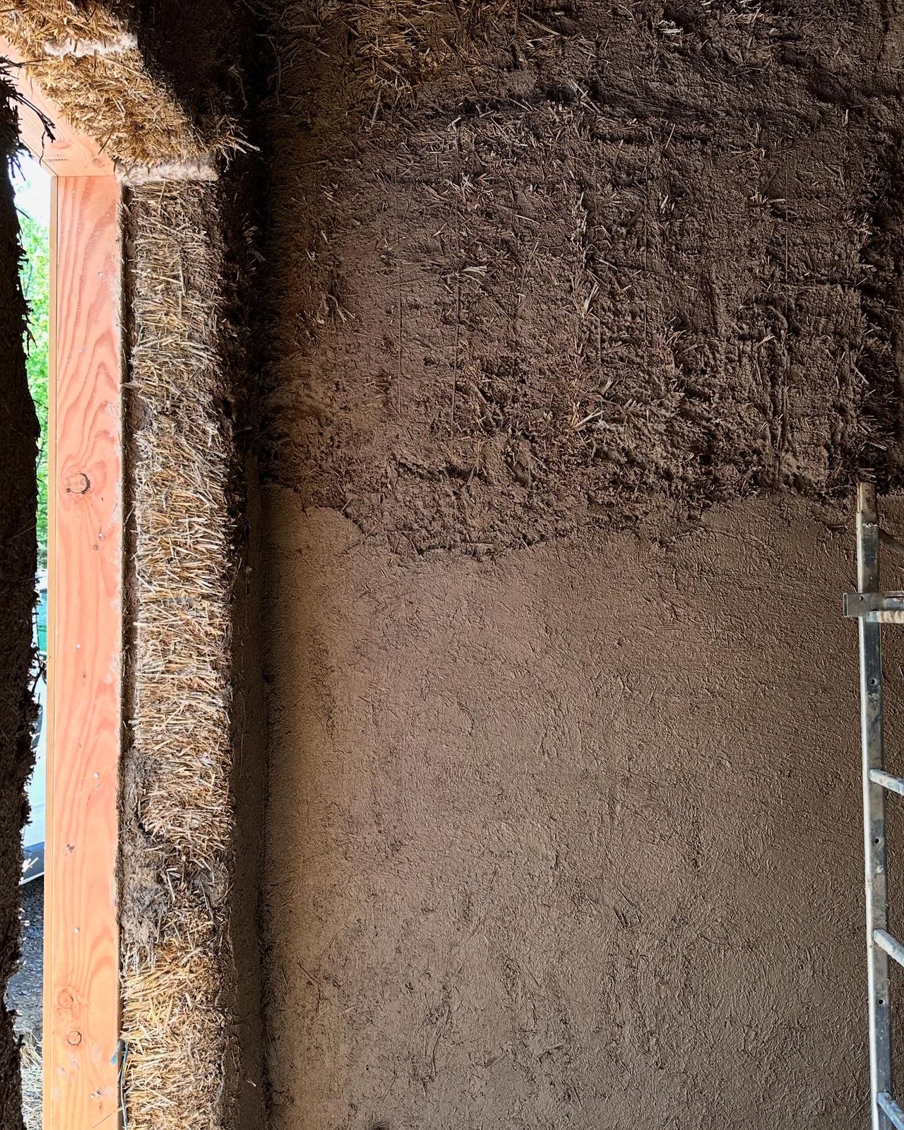 Angle de mur montrant les bottes de paille à gauche et le corps d'enduit terre qui les recouvre à droite